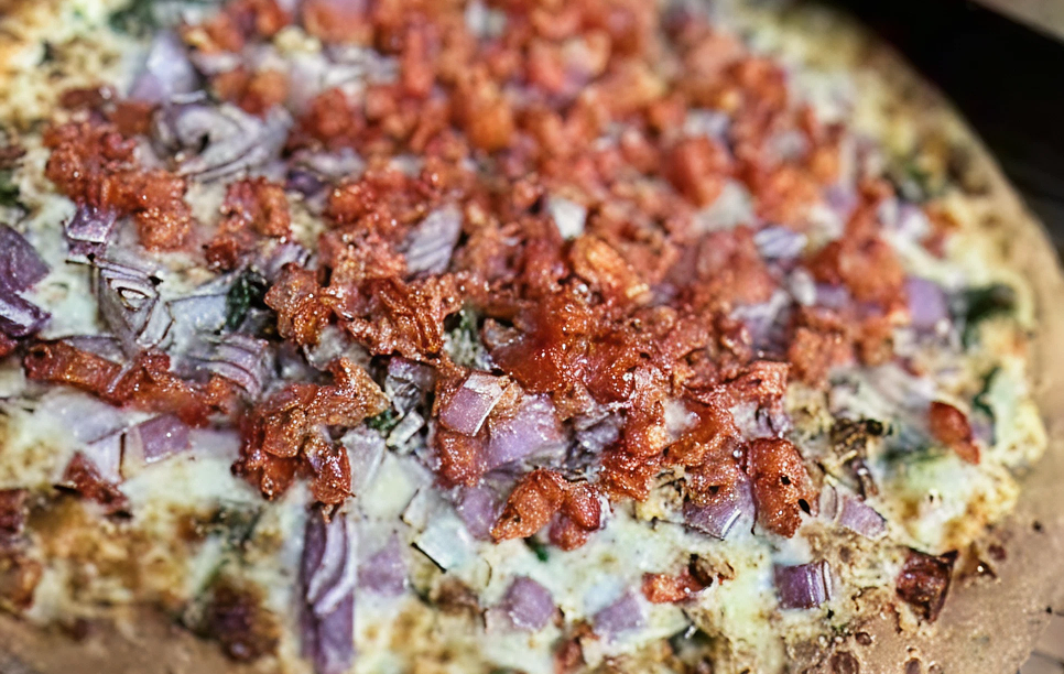 Pizza topped with bacon and red onions.