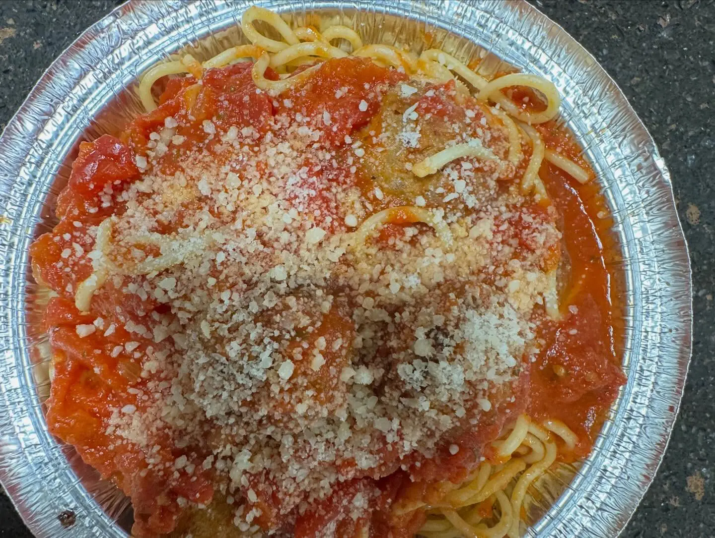 A plate of spaghetti topped with tomato sauce and grated cheese.