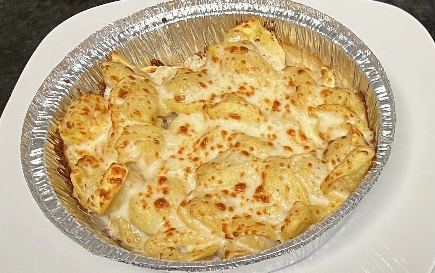 Baked cheesy pasta in a foil container.