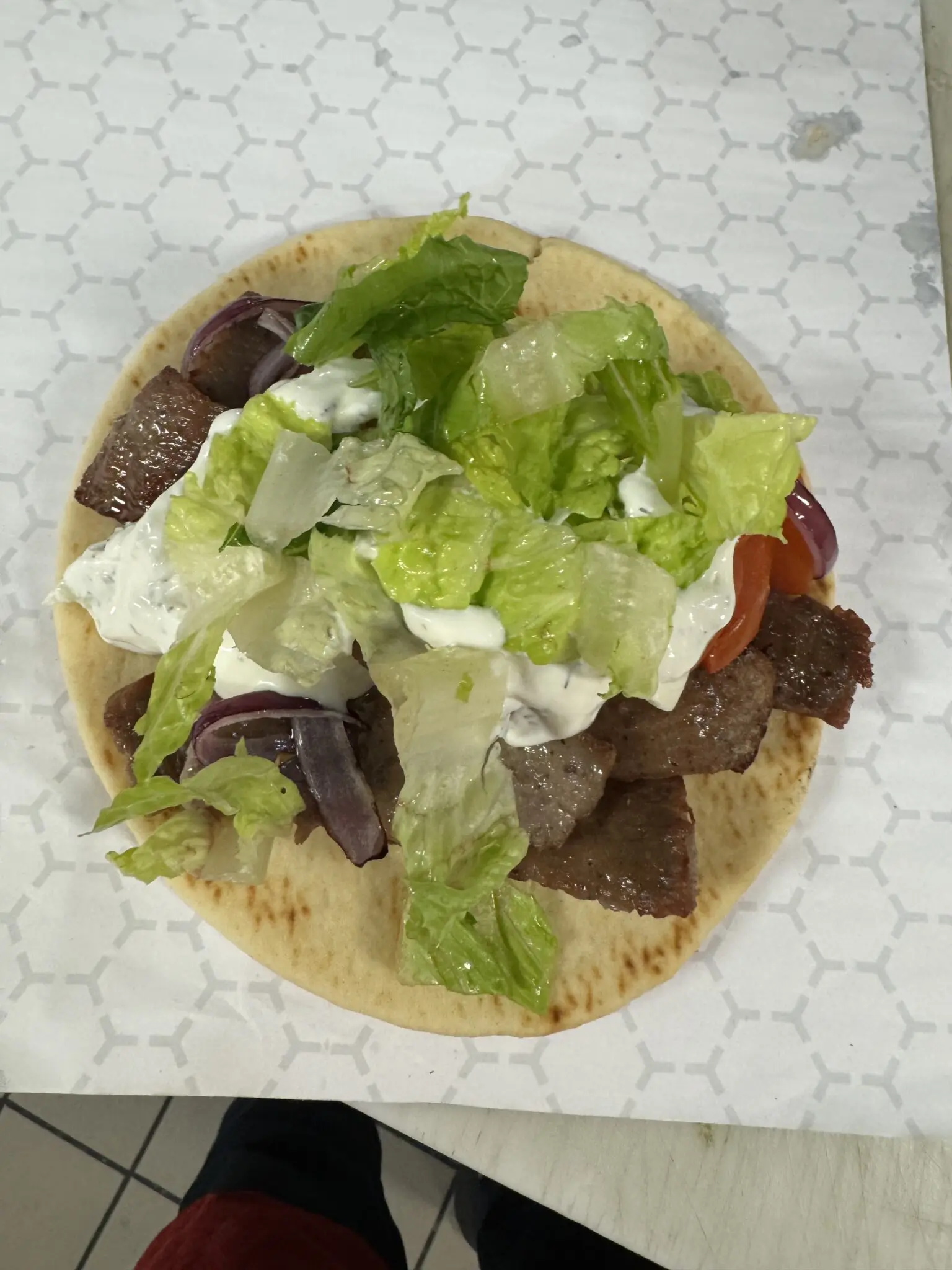 Flatbread topped with meat, lettuce, and sauce.