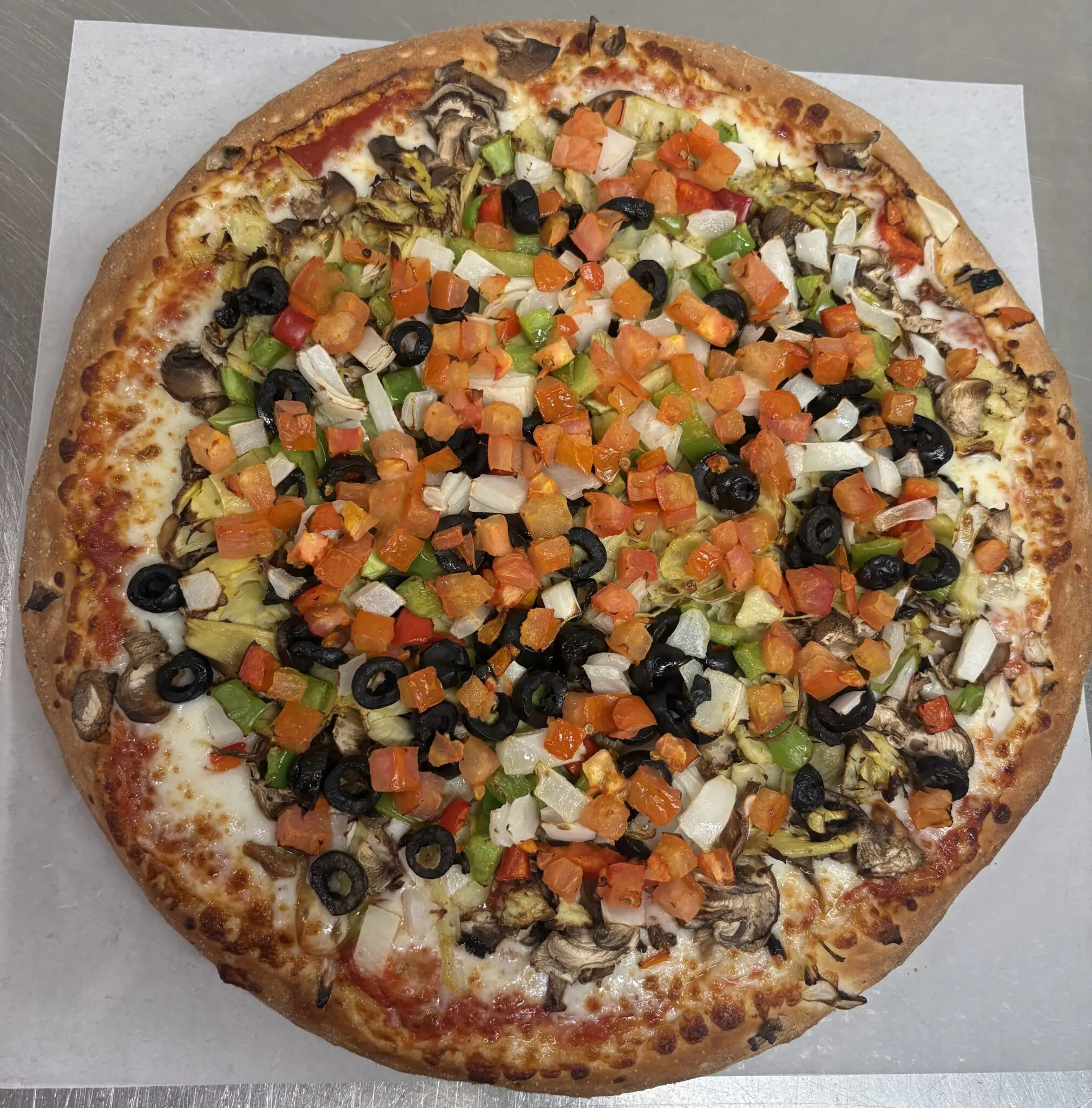 A veggie-loaded pizza with olives, tomatoes, and cheese.