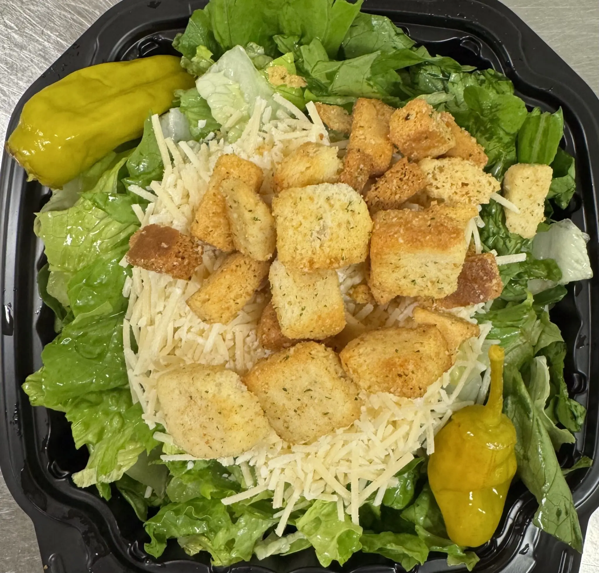 Caesar salad with lettuce, croutons, shredded cheese, and pepperoncini peppers.