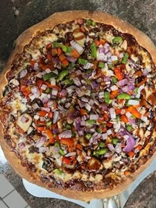 A delicious pizza topped with grilled chicken, red onions, and green bell peppers.