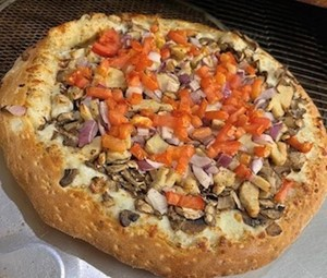 Homemade pizza topped with diced tomatoes and mushrooms.