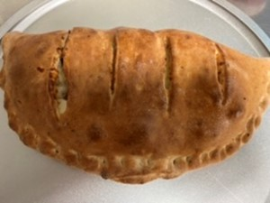 Golden brown baked pastry with slits on top on a white plate.