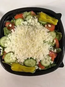Fresh vegetable salad topped with crumbled cheese in a black bowl.