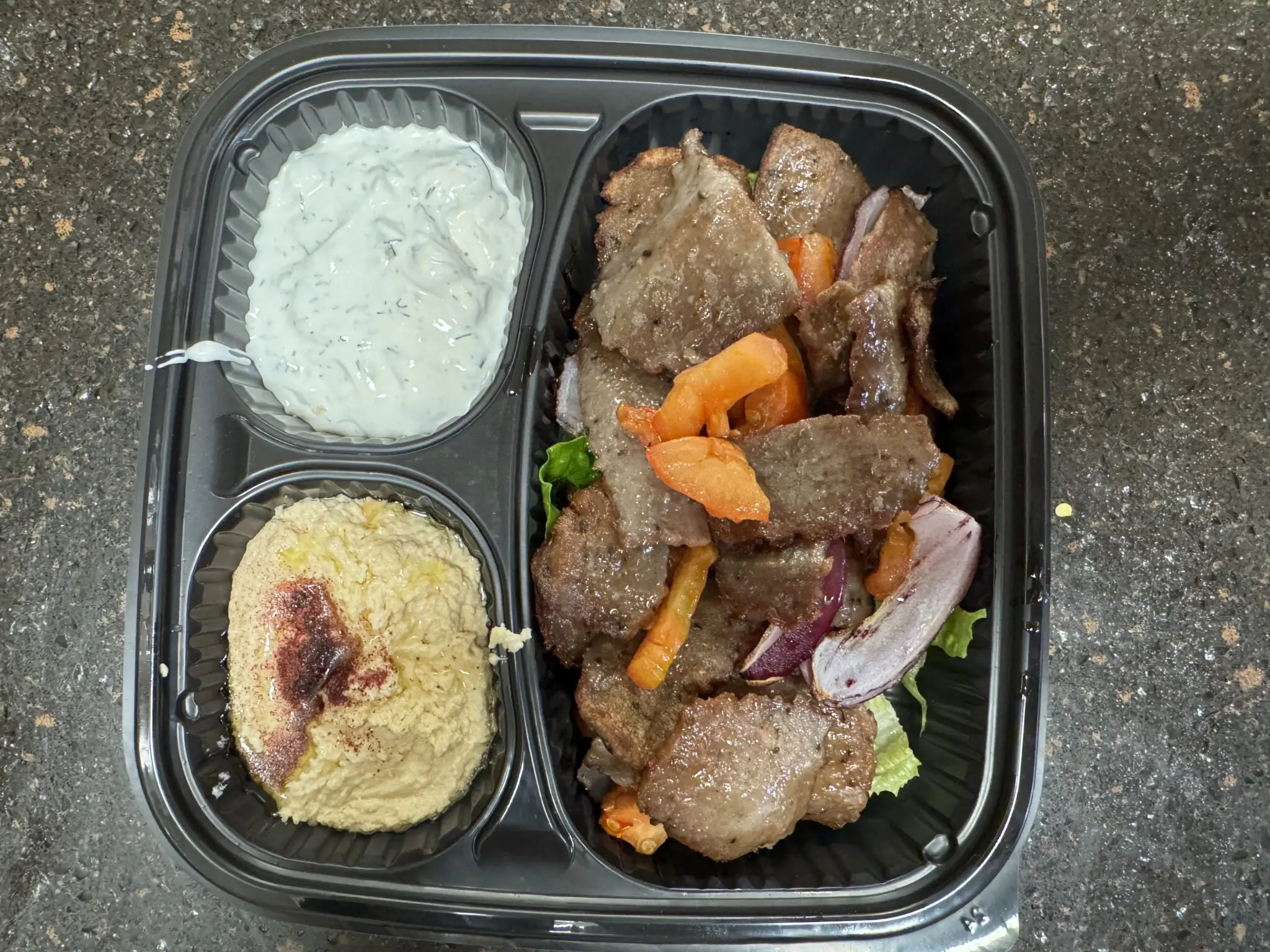 Mediterranean meal with lamb, hummus, and tzatziki sauce.