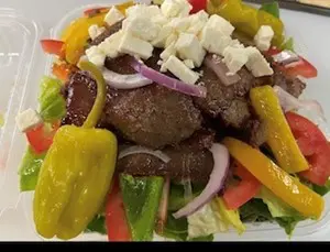 A colorful Greek salad with grilled meat and feta cheese.
