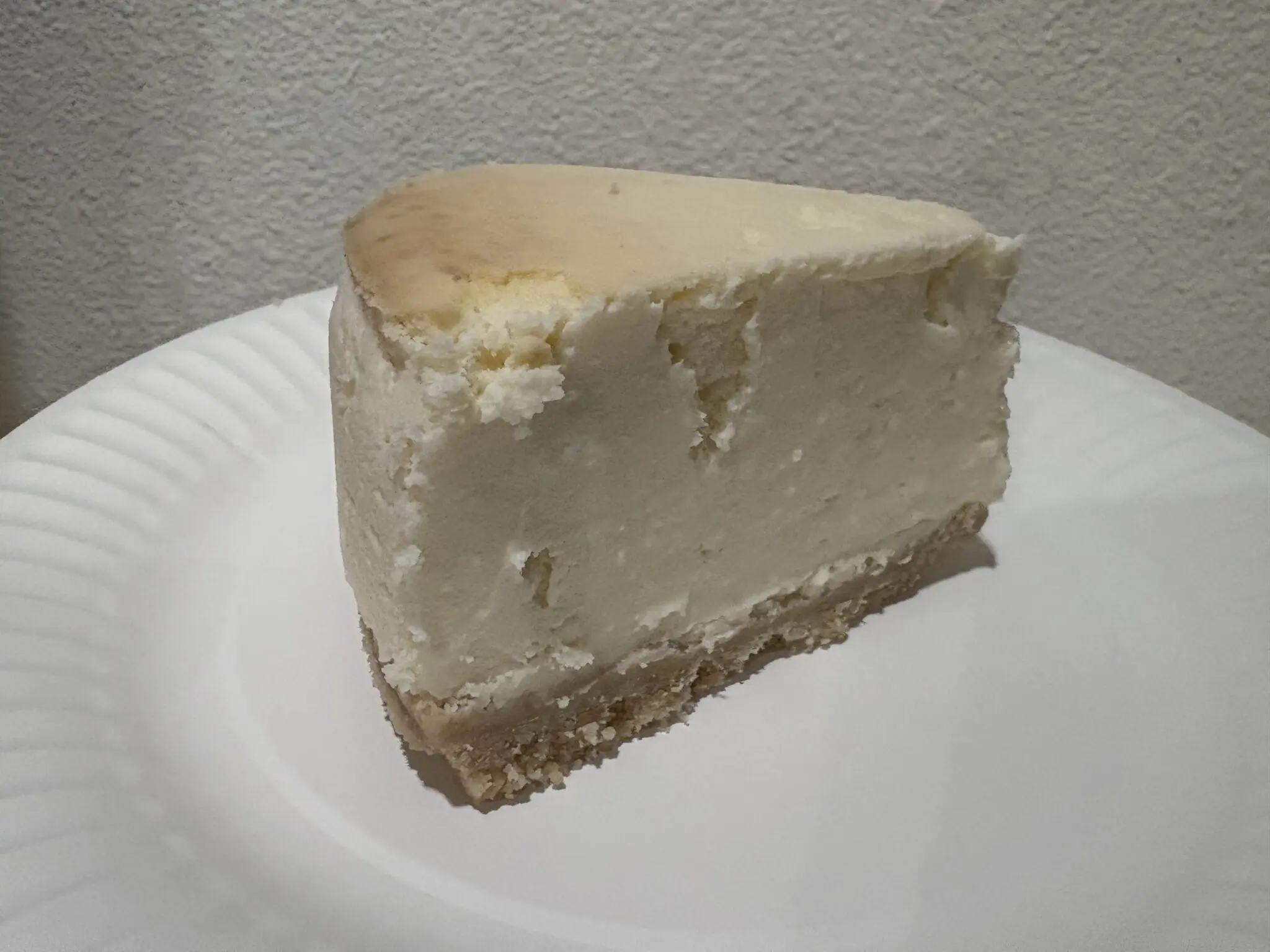 Slice of plain cheesecake on a white plate.