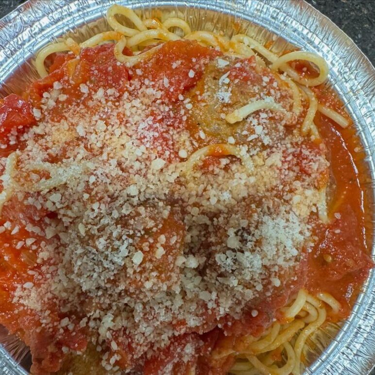 A plate of spaghetti topped with tomato sauce and grated cheese.