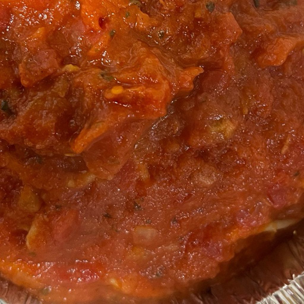 Close-up of a rich, thick tomato sauce with herbs.