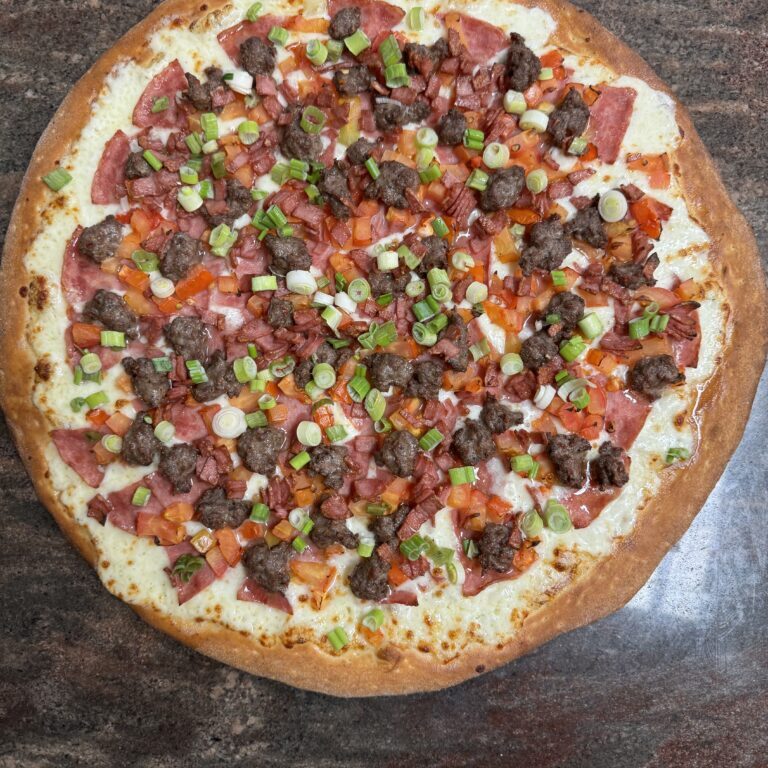 A fully topped pizza with sausage, green peppers, and tomatoes.