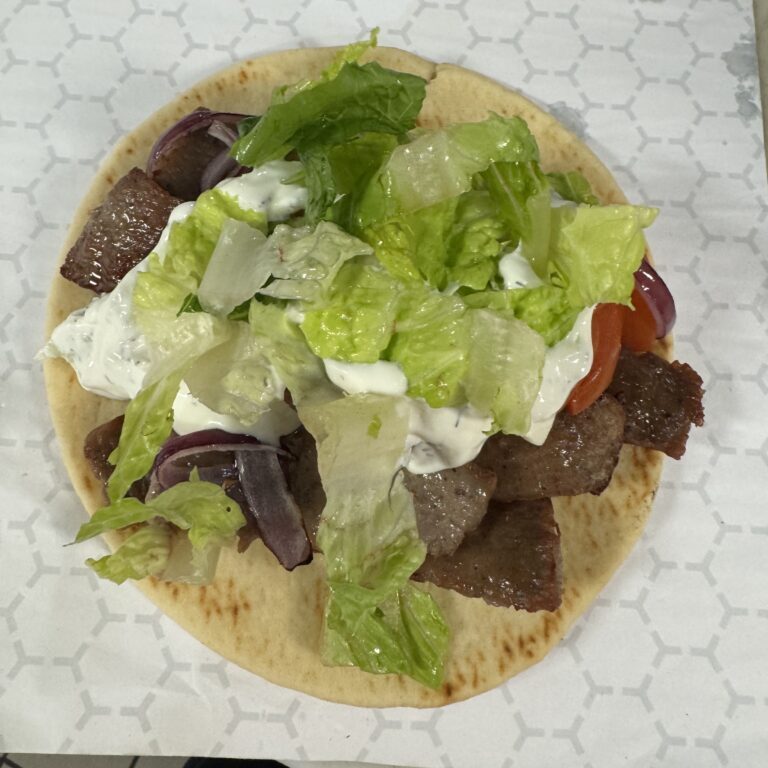 Flatbread topped with meat, lettuce, and sauce.