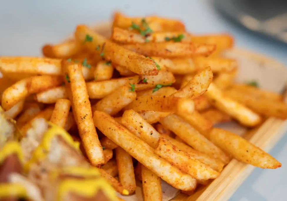 Crispy seasoned French fries garnished with herbs.