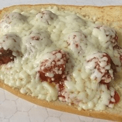 A meatball sandwich topped with melted cheese.