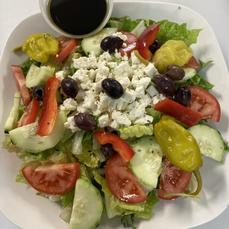 Fresh salad with cottage cheese, olives, and assorted vegetables.