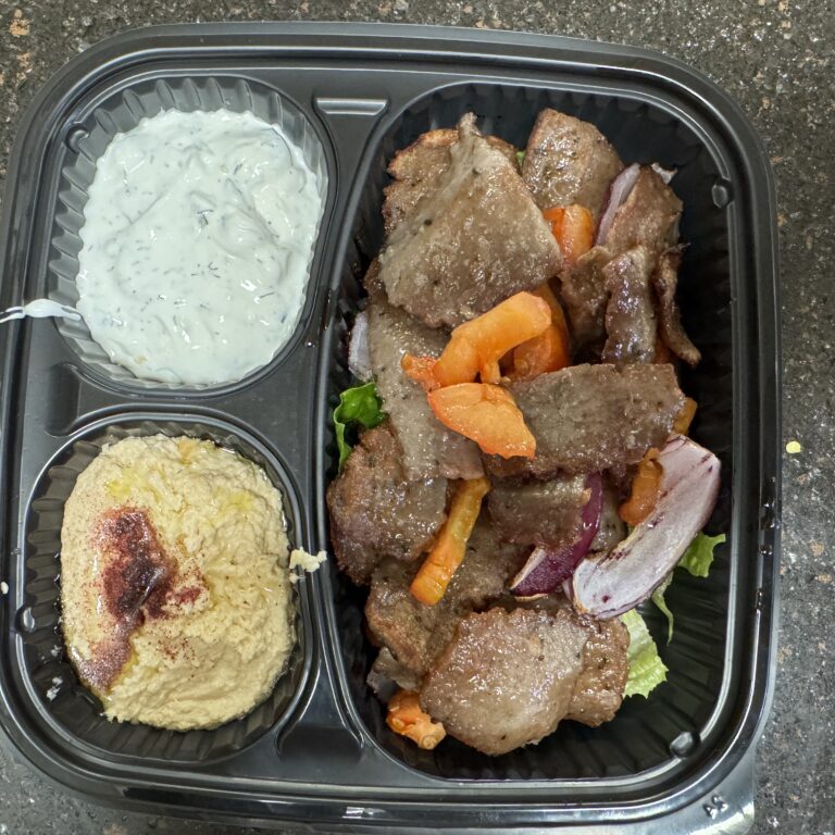 Mediterranean meal with lamb, hummus, and tzatziki sauce.