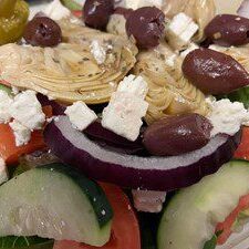 Close-up of a fresh Greek salad with olives, feta, cucumber, and red onion.
